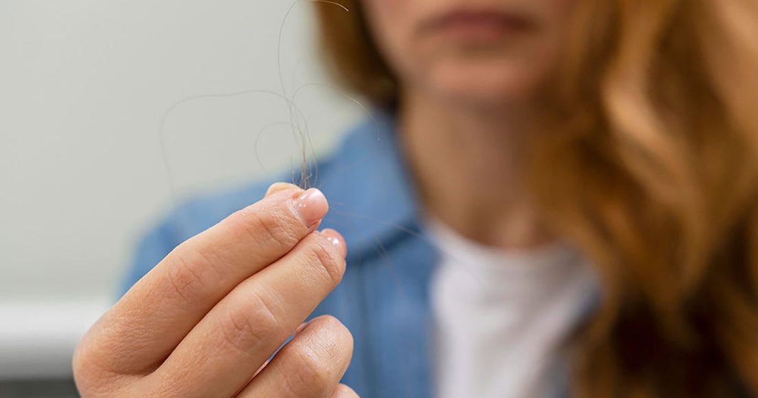Femme rousse regardant sa perte de cheveux dans le miroir